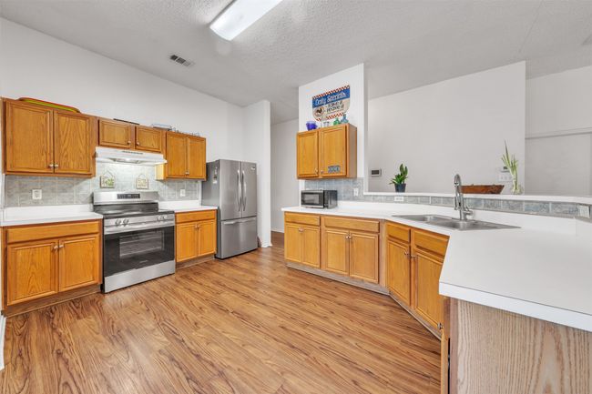Kitchen with appliances with stainless steel finishes, light wood-style flooring, light countertops and backsplash | Image 9