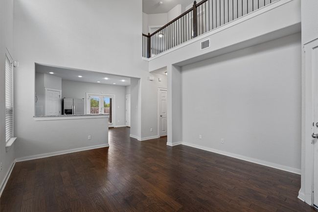 Unfurnished living room with dark wood-style flooring and a high ceiling | Image 11