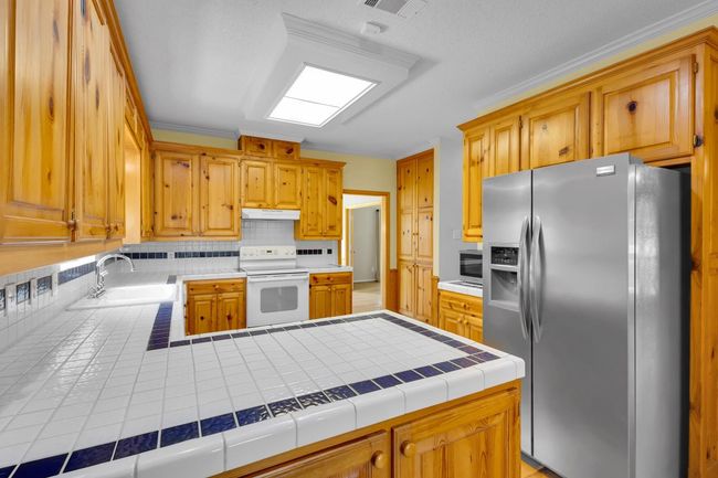 Kitchen with stainless steel appliances, tasteful backsplash, under cabinet range hood, a peninsula, and tile countertops | Image 6