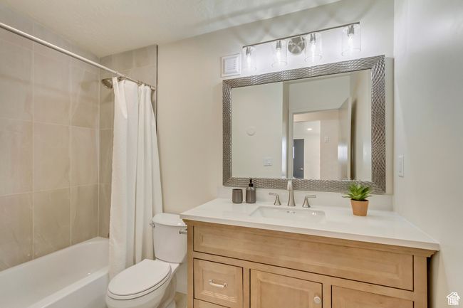 Full bathroom featuring toilet, vanity, and shower / bath combo with shower curtain | Image 16