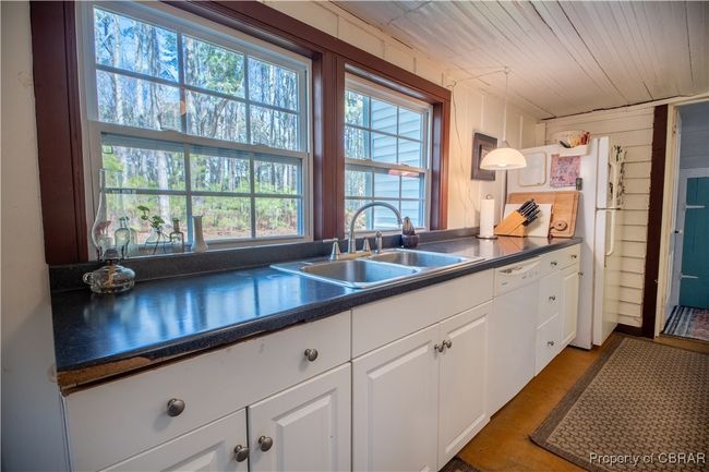 Kitchen featuring dark countertops, white cabinets, dishwasher, and a sink | Image 10