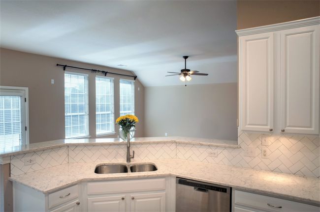 Kitchen featuring dishwasher, a sink, tasteful backsplash, white cabinets, and ceiling fan | Image 4