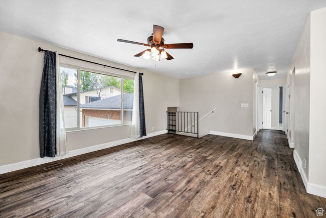 Empty room featuring dark wood-type flooring, a ceiling fan, and baseboards | Image 7