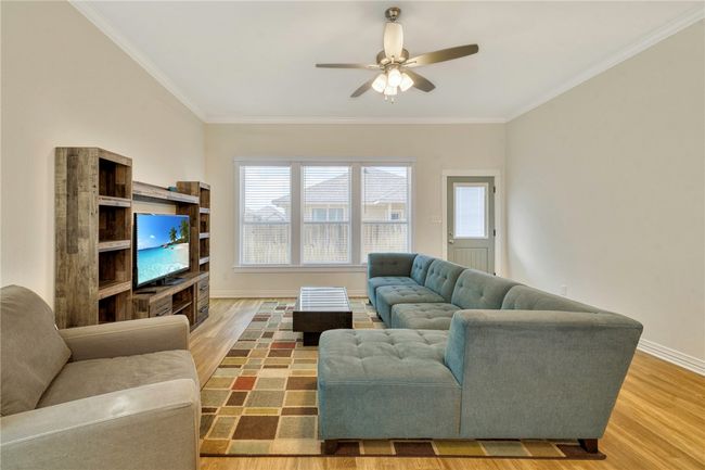 Living area with wood finished floors, ceiling fan, and crown molding | Image 13