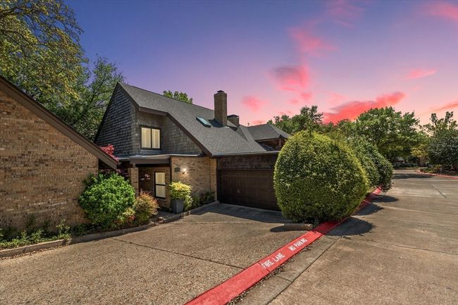 View of front of house featuring a shingled roof, a garage, a chimney, concrete driveway, and brick siding | Image 10