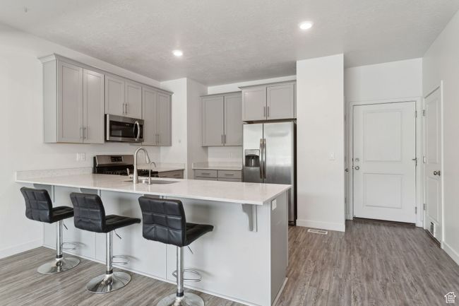Kitchen featuring stainless steel appliances, LVP flooring, peninsula, with quartz countertops, and grey cabinetry | Image 8