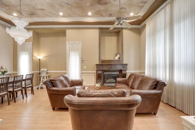 Living room with crown molding, ceiling fan with notable chandelier, light wood-style flooring, and a glass covered fireplace | Image 7