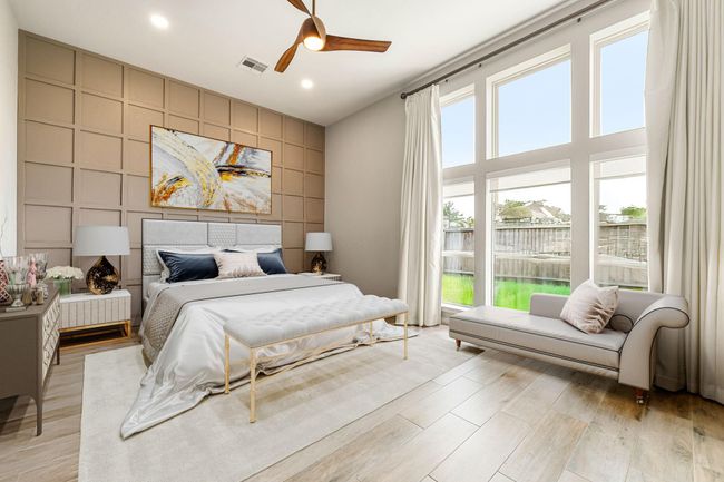 What a wonderful place to come home to! This stunning primary suite greets you with tile floors, custom neutral paint, high ceiling, accent wall, custom ceiling fan with lighting, large windows with blinds allowing in natural light brightening up this spacious primary bedroom with extra space for a seating area. | Image 21