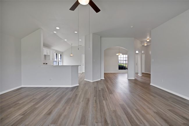 Unfurnished living room featuring arched walkways, a ceiling fan, wood finished floors, baseboards, and recessed lighting | Image 9