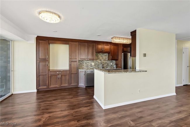 Kitchen with decorative backsplash, light stone counters, dark wood-style flooring, and stainless steel appliances | Image 10