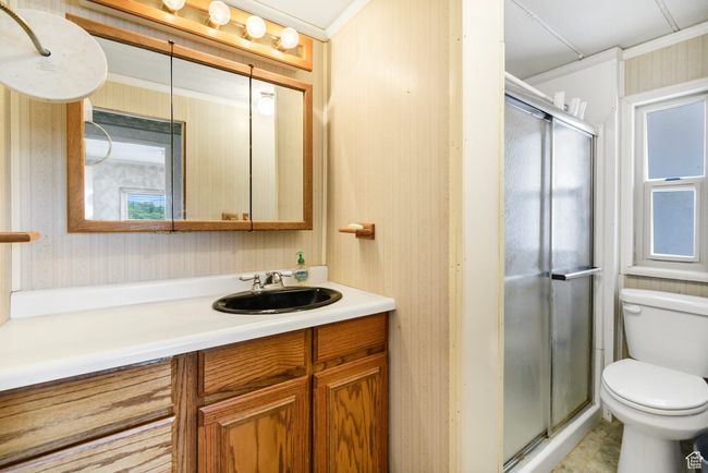 Bathroom featuring wallpapered walls, toilet, vanity, a shower stall, and crown molding | Image 19