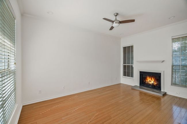 Unfurnished living room with crown molding, a ceiling fan, a glass covered fireplace, and light wood-style floors | Image 4