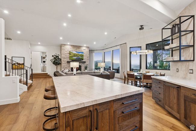 Kitchen featuring light wood-style floors, light countertops, a center island, vaulted ceiling, and pendant lighting | Image 24