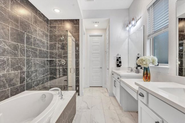 The "wow" factor is built into this master bathroom...the shower stall and bathtub areas area tiled from floor to ceiling. Natural light shines into the built-in make-up desk. The dual sinks are beautiful and complement the entire modern look of this stylish bathroom. | Image 19