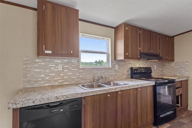 Kitchen with black appliances, under cabinet range hood, tasteful backsplash, and crown molding | Image 15