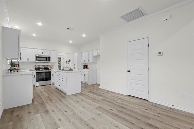 Kitchen featuring white cabinets, a center island, appliances with stainless steel finishes, and crown molding | Image 13