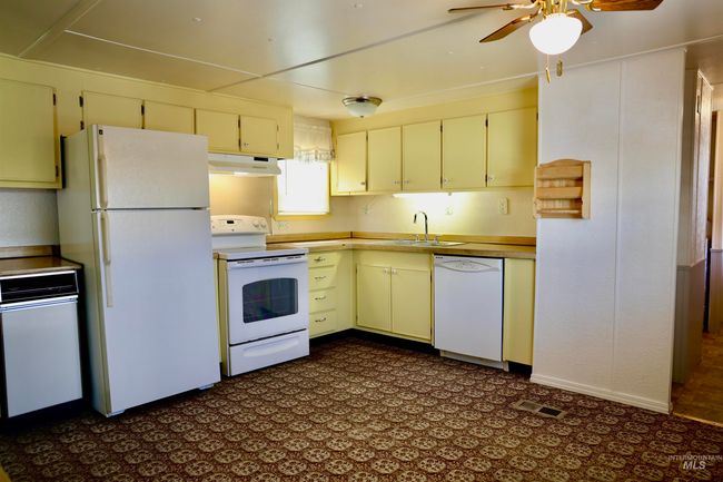 Kitchen featuring white appliances, under cabinet range hood, ceiling fan, and cream cabinets | Image 7