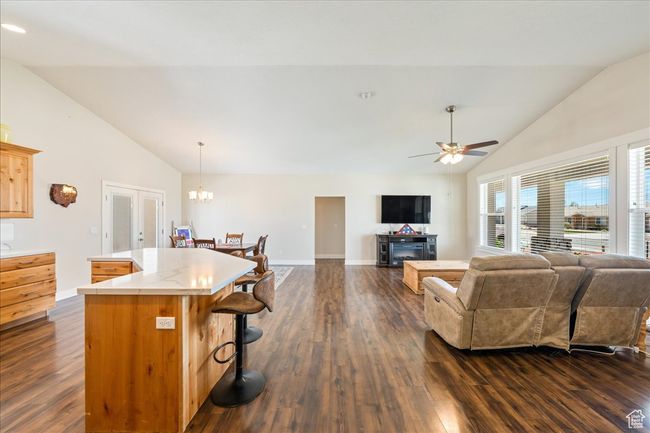 Living area with high vaulted ceiling, dark wood finished floors, baseboards, and ceiling fan with notable chandelier | Image 10