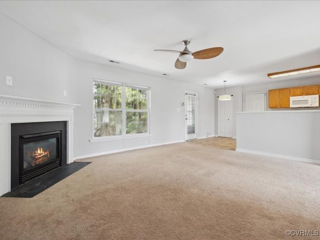 Unfurnished living room with light carpet, ceiling fan, and a fireplace with flush hearth | Image 13