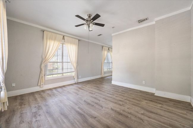 Empty room with crown molding, a ceiling fan, and wood finished floors | Image 4