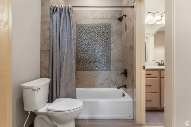Connected bathroom featuring shower / tub combo with curtain, tile patterned flooring, vanity, and toilet | Image 22