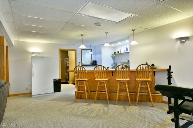 Carpeted dining room featuring bar area, a drop ceiling, and baseboards | Image 36