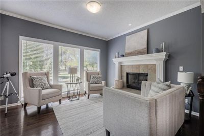 Living room featuring ornamental molding, dark wood-type flooring, a tiled fireplace, and a textured ceiling | Image 2