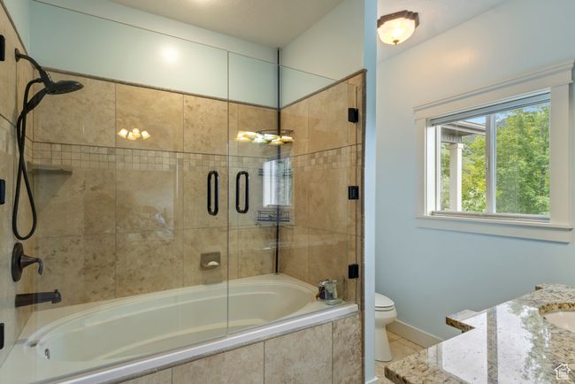 Bathroom featuring tiled shower / bath combo, toilet, tile patterned flooring, and baseboards | Image 20