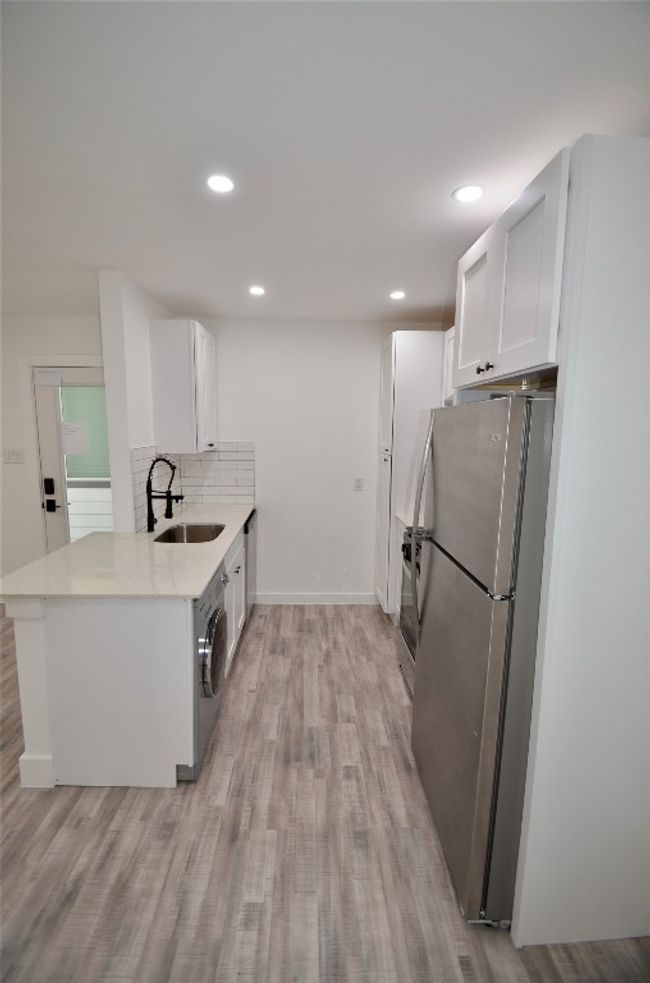 Kitchen featuring freestanding refrigerator, white cabinetry, light wood finished floors, light countertops, and recessed lighting | Image 5
