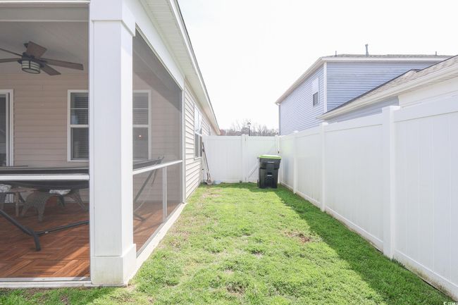 View of yard featuring a fenced backyard, a ceiling fan, and a sunroom | Image 29