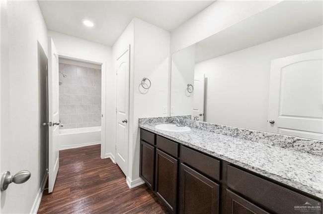 Full bathroom featuring wood finished floors, vanity, baseboards, shower / tub combination, and recessed lighting | Image 25