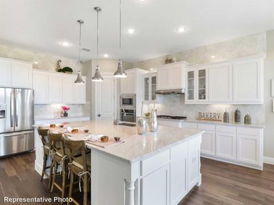 Kitchen with dark hardwood / wood-style flooring, stainless steel appliances, hanging light fixtures, and an island with sink | Image 2