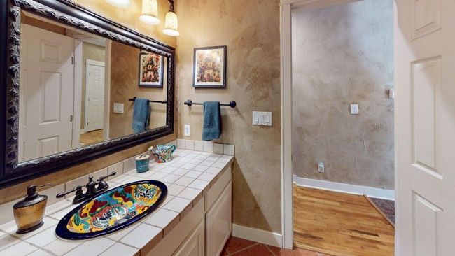 Main house second bathroom with vanity and wood floors. Baths in the main house feature talavera sinks and custom mirrors | Image 19