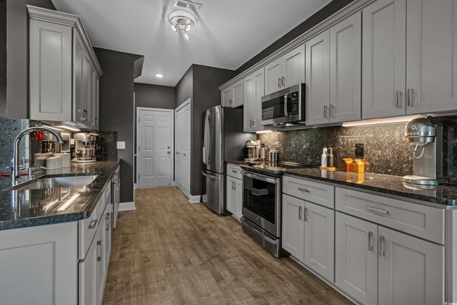 Kitchen featuring stainless steel appliances, decorative backsplash, wood finished floors, recessed lighting, and dark stone counters | Image 15