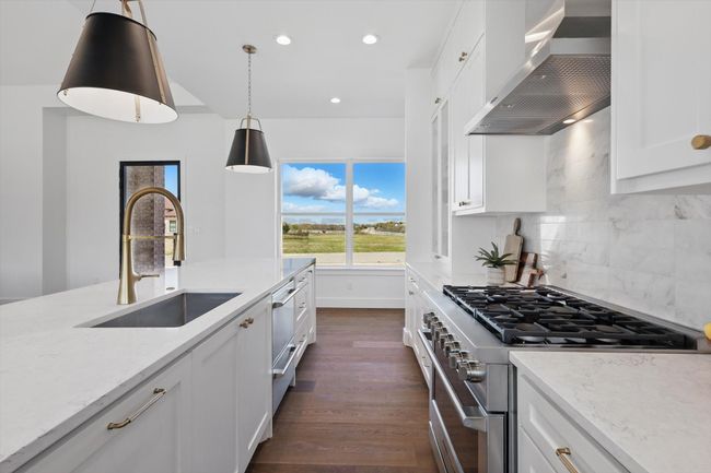Kitchen featuring backsplash, a sink, white cabinets, high end range, and wall chimney exhaust hood | Image 10