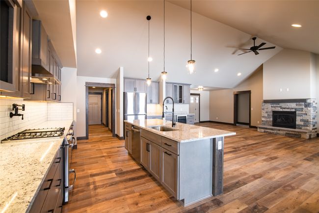 Kitchen featuring sink, hanging light fixtures, stainless steel appliances, light stone counters, and a center island with sink | Image 9