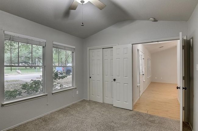 Unfurnished bedroom with lofted ceiling, light colored carpet, a closet, and a ceiling fan | Image 25