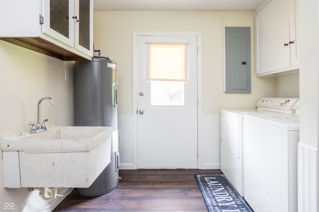laundry area featuring cabinet space, washing machine and dryer, dark wood-style floors, electric panel, and a wainscoted wall | Image 32