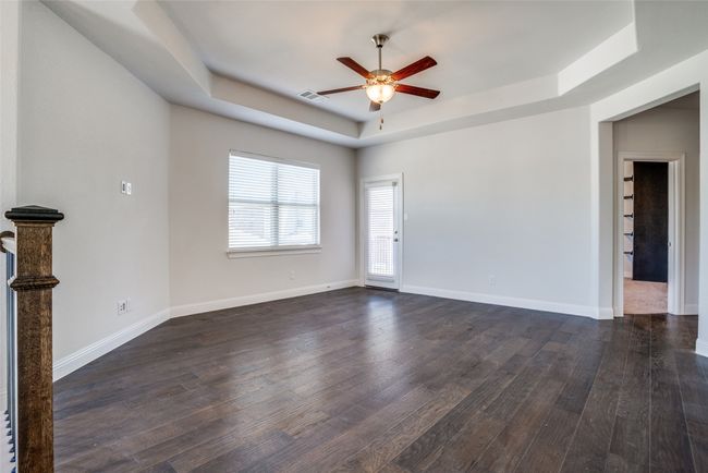 Empty room with a tray ceiling, a ceiling fan, and dark wood-type flooring | Image 13