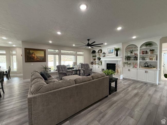 Living room with light wood-style floors, ceiling fan, and a textured ceiling | Image 10
