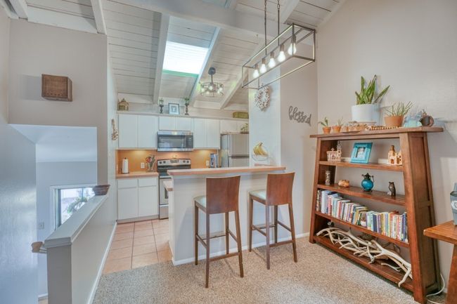 Kitchen featuring stainless steel appliances, a kitchen bar, light colored carpet, and white cabinets upper unit | Image 19