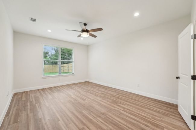 Primary bedroom with light wood-style flooring, visible vents, a ceiling fan, and baseboards | Image 22
