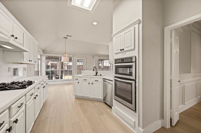 Kitchen with vaulted ceiling, a sink, white cabinetry, appliances with stainless steel finishes, and a peninsula | Image 18