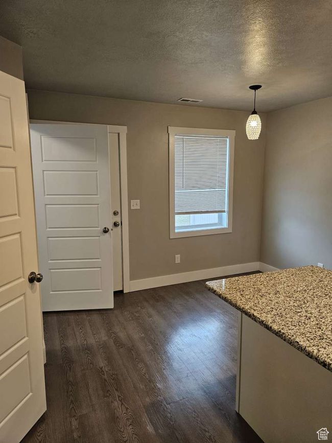Unfurnished dining area with a textured ceiling, dark wood-style flooring, baseboards, and visible vents | Image 5