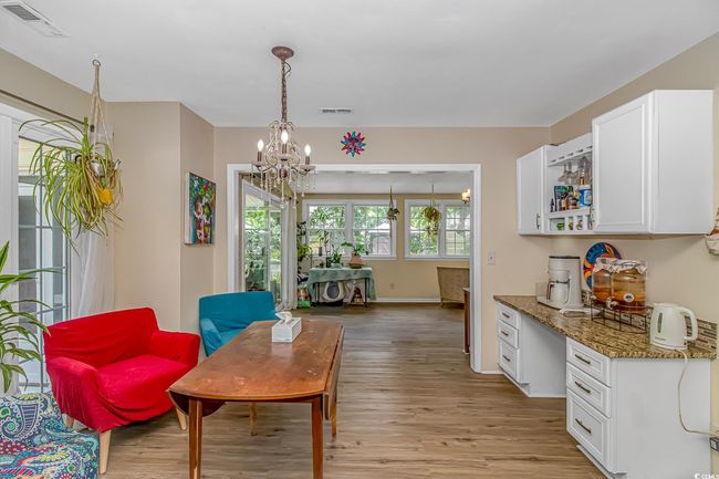 Living area featuring light wood-style floors, a chandelier, and a desk | Image 13