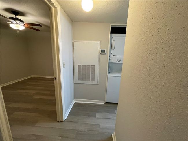 Corridor featuring stacked washing maching and dryer, a textured ceiling, and hardwood / wood-style flooring | Image 11