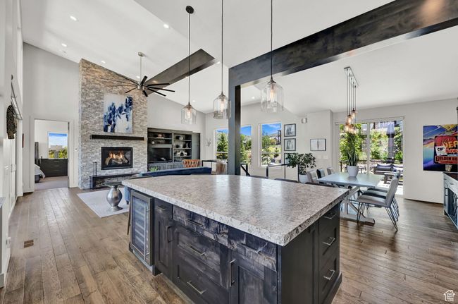 Kitchen featuring a fireplace, a ceiling fan, beverage cooler, dark cabinets, and hardwood floors | Image 20