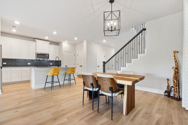Dining room with a chandelier, light wood finished floors, recessed lighting, stairway, and baseboards | Image 4