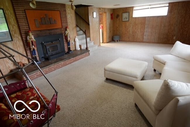 carpeted living area featuring wooden walls and stairway | Image 34