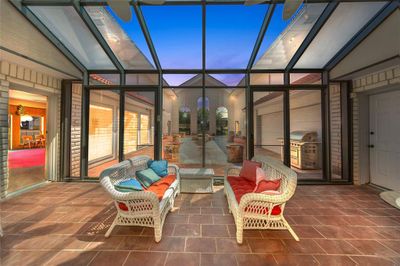 Patio terrace at dusk featuring glass enclosure and area for grilling | Image 3